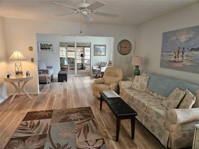 living room with a textured ceiling, light hardwood / wood-style flooring, and ceiling fan