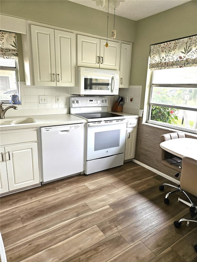 kitchen with white appliances, white cabinets, sink, light wood-type flooring, and tasteful backsplash