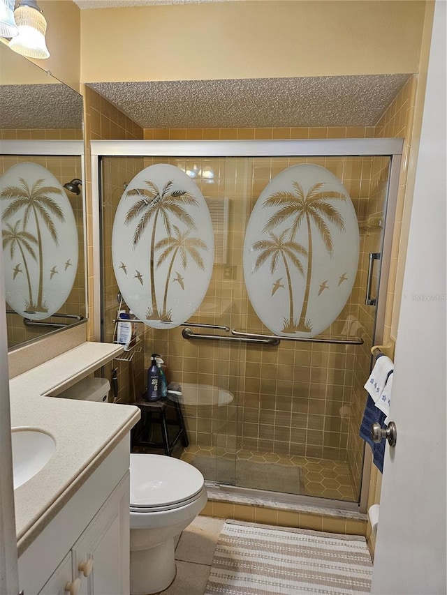 bathroom with toilet, vanity, tile patterned floors, and a shower with shower door