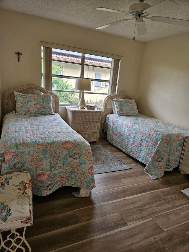 bedroom featuring ceiling fan, dark hardwood / wood-style flooring, and a textured ceiling