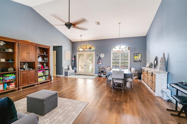 living room featuring french doors, ceiling fan with notable chandelier, hardwood / wood-style flooring, and high vaulted ceiling