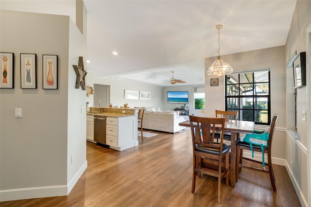 dining room with hardwood / wood-style floors, ceiling fan with notable chandelier, and sink