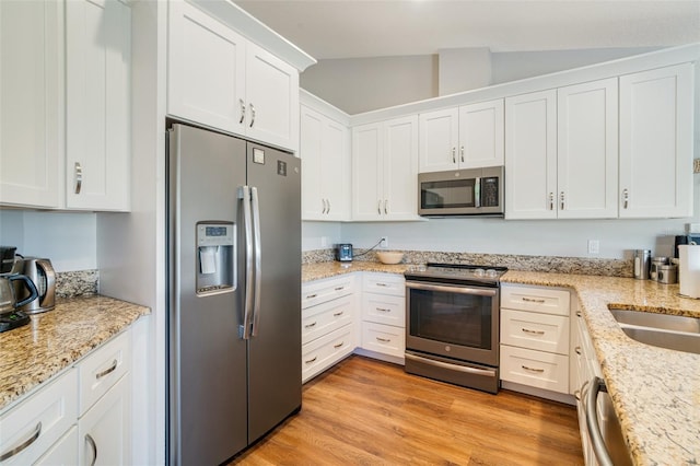 kitchen featuring white cabinets, light hardwood / wood-style floors, appliances with stainless steel finishes, and vaulted ceiling