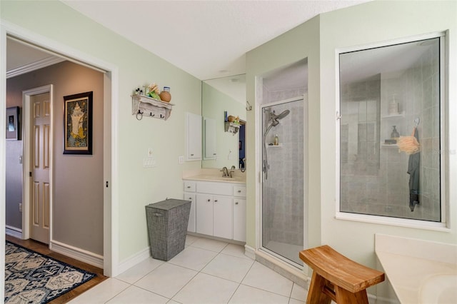 bathroom with tile patterned flooring, vanity, a shower with shower door, and ornamental molding