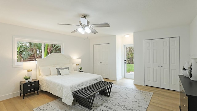 bedroom featuring multiple windows, ceiling fan, light hardwood / wood-style flooring, and multiple closets