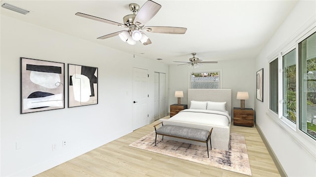 bedroom featuring multiple closets, ceiling fan, and light wood-type flooring