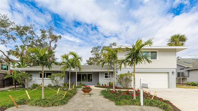 split level home with stucco siding, driveway, fence, and a garage
