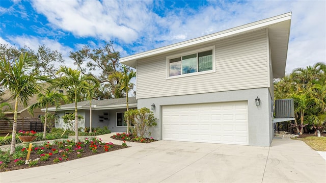 traditional-style home featuring a garage, stucco siding, cooling unit, and concrete driveway