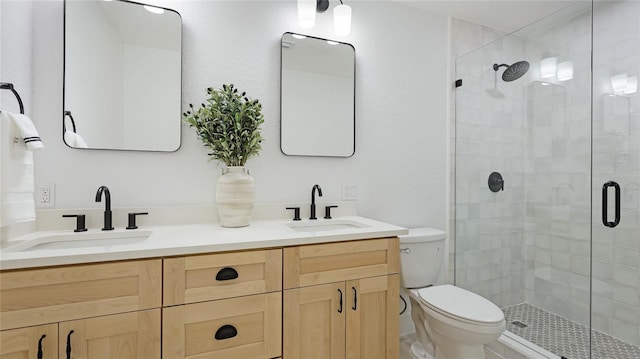 full bathroom with a sink, a shower stall, double vanity, and toilet