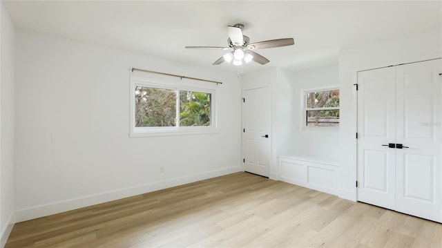 unfurnished bedroom with light wood-type flooring, multiple closets, a ceiling fan, and baseboards
