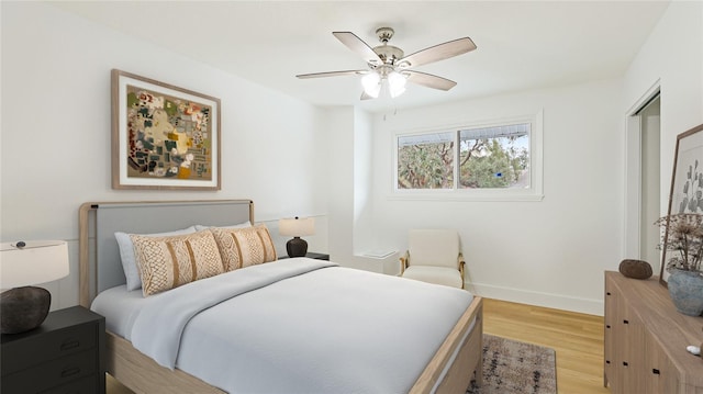bedroom featuring light wood-type flooring, a ceiling fan, and baseboards