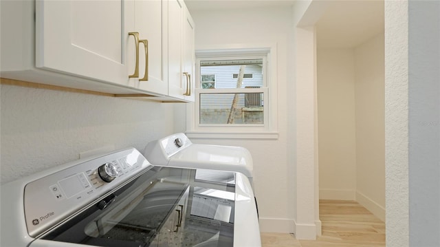 clothes washing area with baseboards, washing machine and clothes dryer, cabinet space, and light wood-style flooring