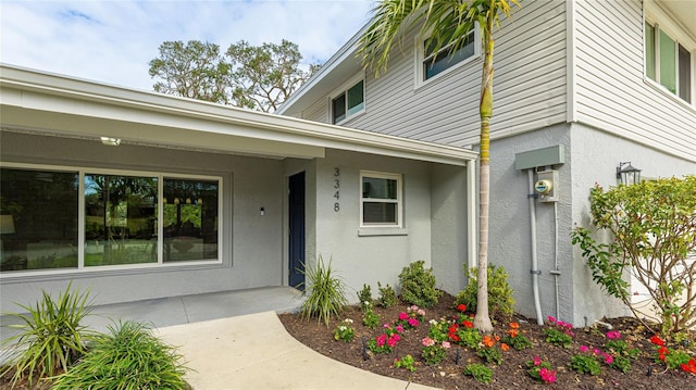 property entrance with stucco siding and covered porch