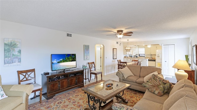 living room featuring ceiling fan and a textured ceiling