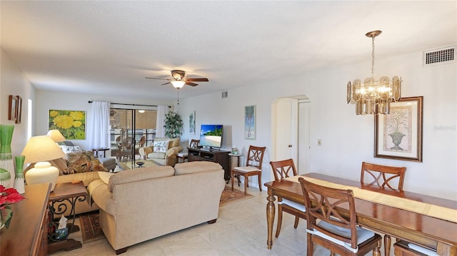 living room featuring a textured ceiling and ceiling fan with notable chandelier