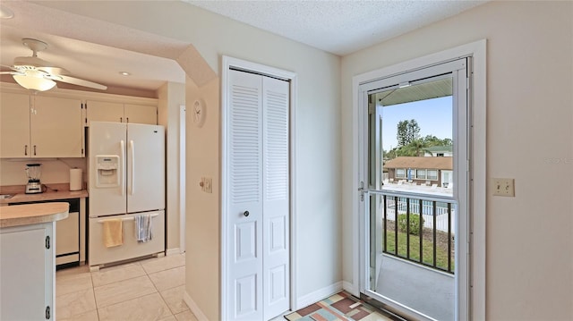 entryway featuring a textured ceiling, ceiling fan, and light tile patterned flooring