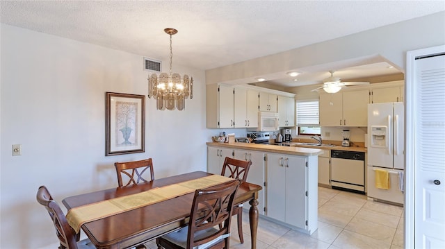 dining room featuring ceiling fan with notable chandelier, sink, light tile patterned floors, and a textured ceiling