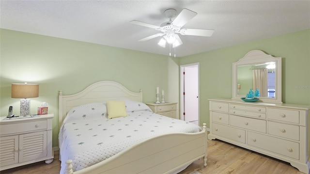 bedroom featuring ceiling fan, light hardwood / wood-style floors, and a textured ceiling