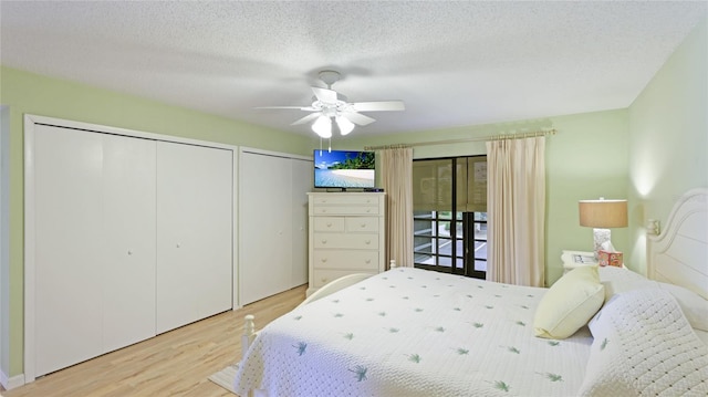 bedroom featuring access to outside, two closets, light hardwood / wood-style flooring, ceiling fan, and a textured ceiling