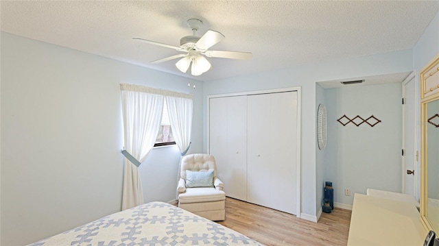 bedroom with ceiling fan, a closet, light hardwood / wood-style floors, and a textured ceiling