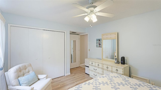 bedroom with ceiling fan, light hardwood / wood-style floors, a textured ceiling, and a closet