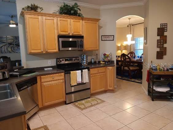 kitchen featuring stainless steel appliances, crown molding, light tile patterned floors, a chandelier, and hanging light fixtures