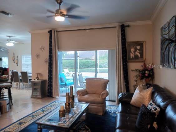 living room with tile patterned floors, ceiling fan, and ornamental molding