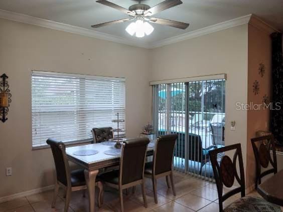 tiled dining space with ceiling fan and ornamental molding