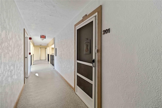 hall with a textured ceiling and light carpet