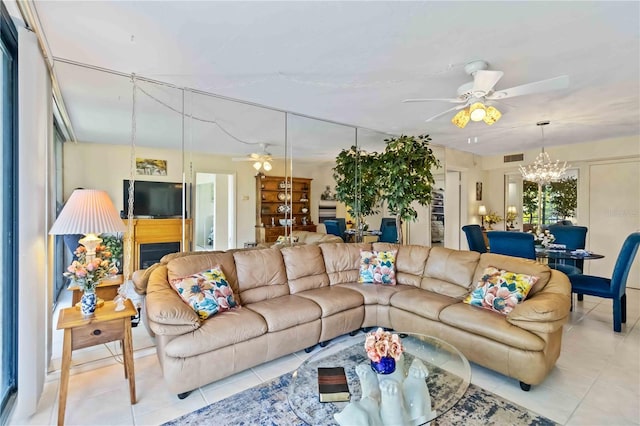 tiled living room with ceiling fan with notable chandelier