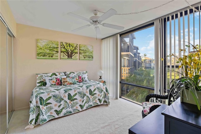 bedroom featuring ceiling fan, a closet, carpet floors, and a wall of windows