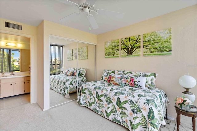 bedroom with light carpet, sink, ensuite bath, ceiling fan, and a closet