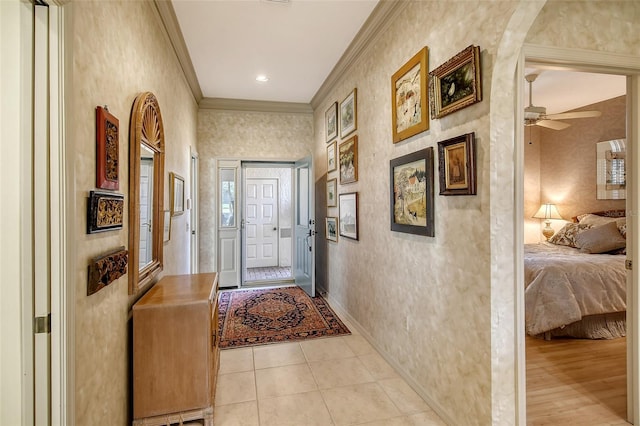 doorway featuring ceiling fan, light tile patterned floors, and crown molding