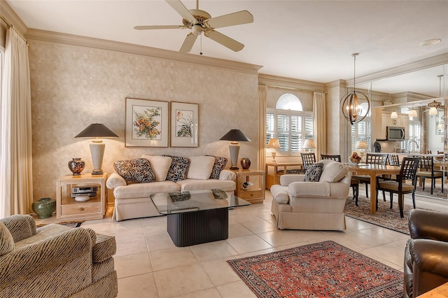 living room featuring light tile patterned floors, ceiling fan with notable chandelier, and crown molding