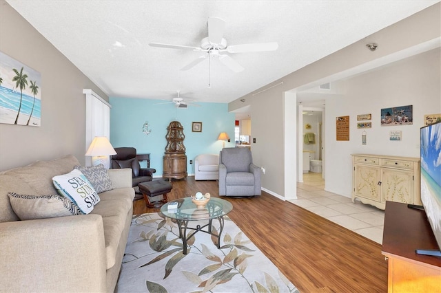 living room featuring a textured ceiling, light hardwood / wood-style floors, and ceiling fan