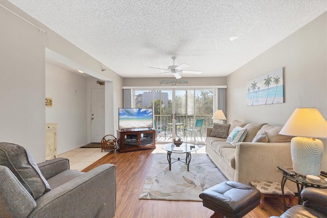 living room with ceiling fan, light hardwood / wood-style floors, and a textured ceiling