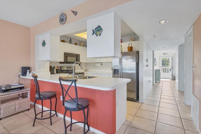 kitchen featuring kitchen peninsula, stainless steel refrigerator with ice dispenser, a kitchen breakfast bar, sink, and white cabinets