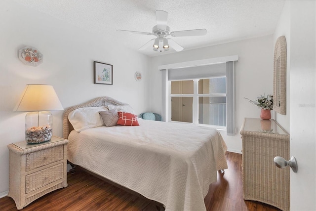 bedroom with ceiling fan, dark wood-type flooring, and a textured ceiling