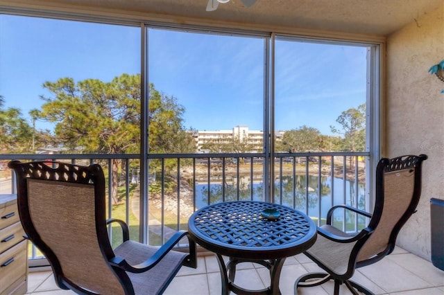 sunroom with ceiling fan and a water view