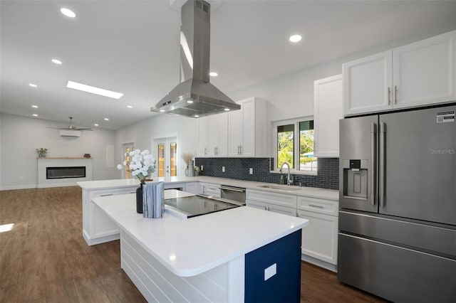 kitchen with white cabinets, sink, kitchen peninsula, island exhaust hood, and stainless steel appliances