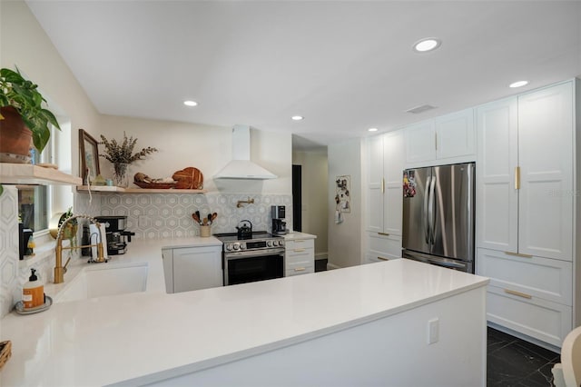 kitchen featuring appliances with stainless steel finishes, tasteful backsplash, sink, white cabinets, and wall chimney exhaust hood