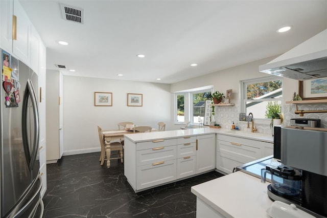 kitchen with sink, white cabinetry, tasteful backsplash, stainless steel refrigerator, and kitchen peninsula