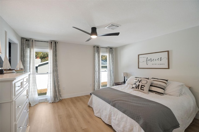 bedroom with ceiling fan, light hardwood / wood-style floors, and a textured ceiling