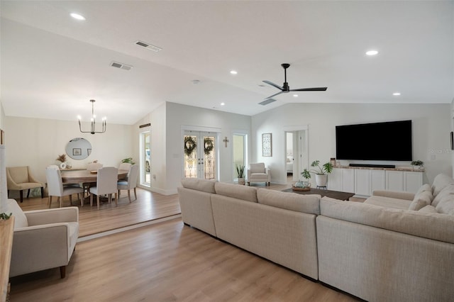 living room with french doors, vaulted ceiling, ceiling fan with notable chandelier, and light hardwood / wood-style flooring