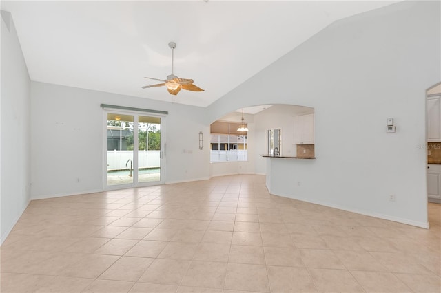 unfurnished living room featuring ceiling fan with notable chandelier, light tile patterned flooring, and vaulted ceiling