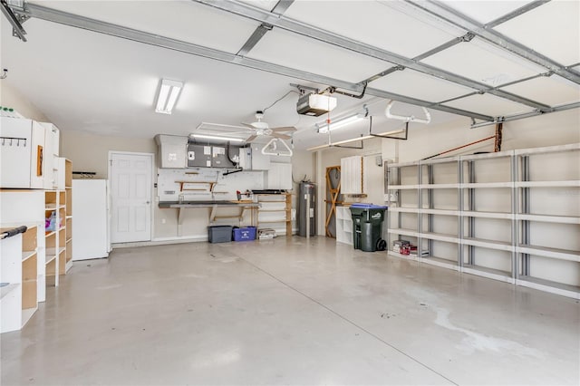 garage featuring electric water heater, a workshop area, white fridge, and a garage door opener