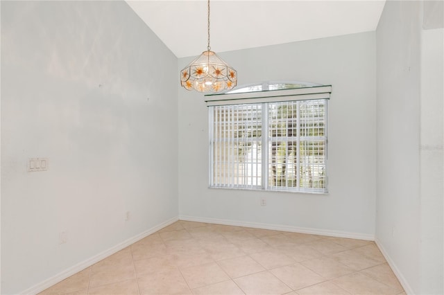 tiled spare room featuring lofted ceiling and a chandelier