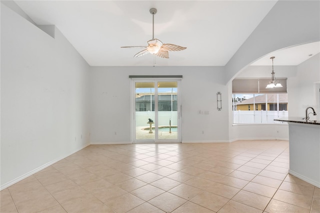 unfurnished living room featuring ceiling fan with notable chandelier, sink, a wealth of natural light, and light tile patterned floors