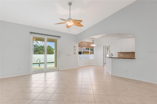 unfurnished living room featuring lofted ceiling, light tile patterned flooring, and ceiling fan with notable chandelier