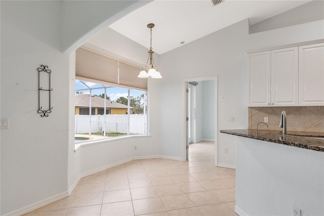 unfurnished dining area with light tile patterned floors, lofted ceiling, and a notable chandelier